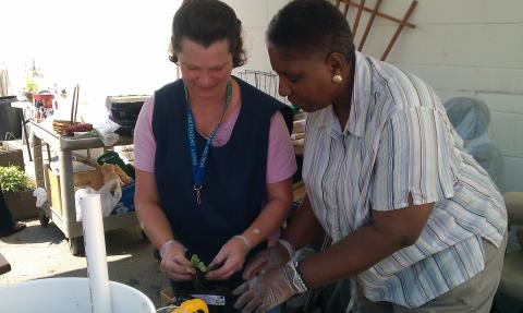 Course instructor teaches woman with a disability how to plant a container gardent of her own using recycled materials