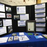 A table top display with information about Walton Options, the City of Augusta ADA25 Celebration Proclamation, and a black and white sketch of Justin Dart.
