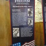 A roll-up banner with information about the Road to the ADA. There is text along with black and white images during the disability rights movement leading up to the signing of the ADA.