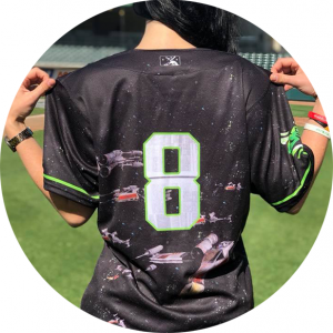 Photo: a person standing on a baseball field showing off the back of a baseball Jersey with the number '8' and Star Wars spaceships.
