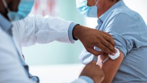 Image of a doctor administering a shot into a patients arm.