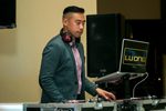 DJ Lu Ong at his computer wearing headphones around his neck and working his turn-table