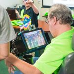 A Walton Options' staff member uses his assistive technology to speak with one of the parents while he sits in his wheelchair.
