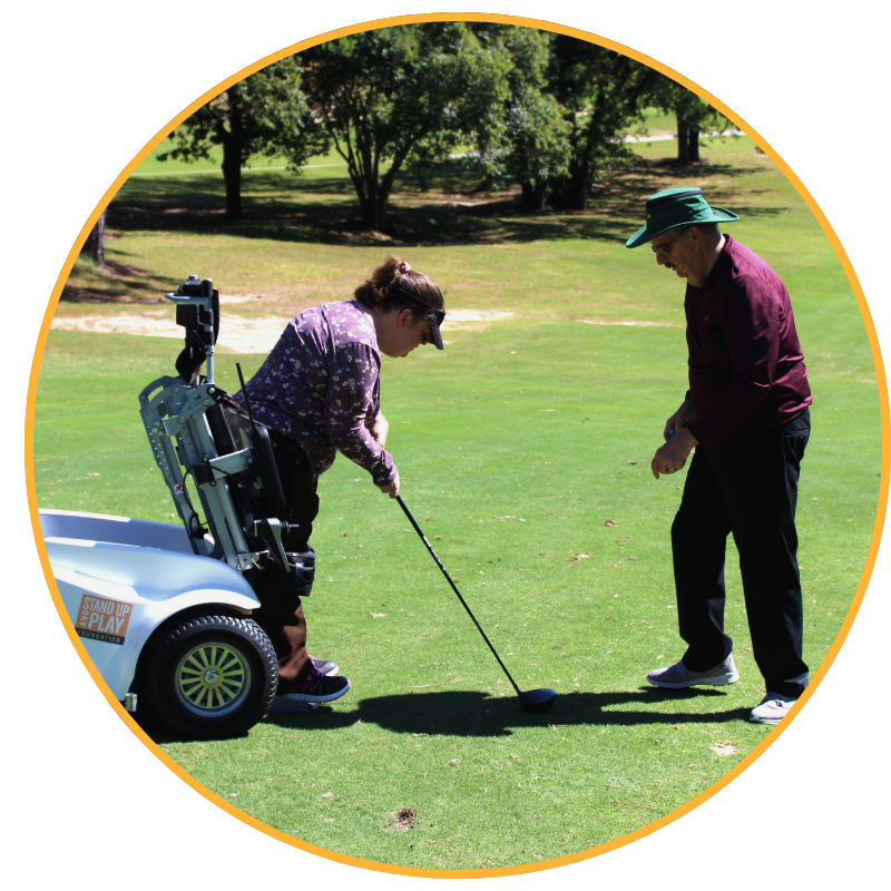 Image is a circle shape with a yellow border. In the background is a golf course. In the fore ground is a woman using an adaptive golf chair preparing to hit a golf ball with a club. On the right is a man preparing to put down a tee and golf ball
